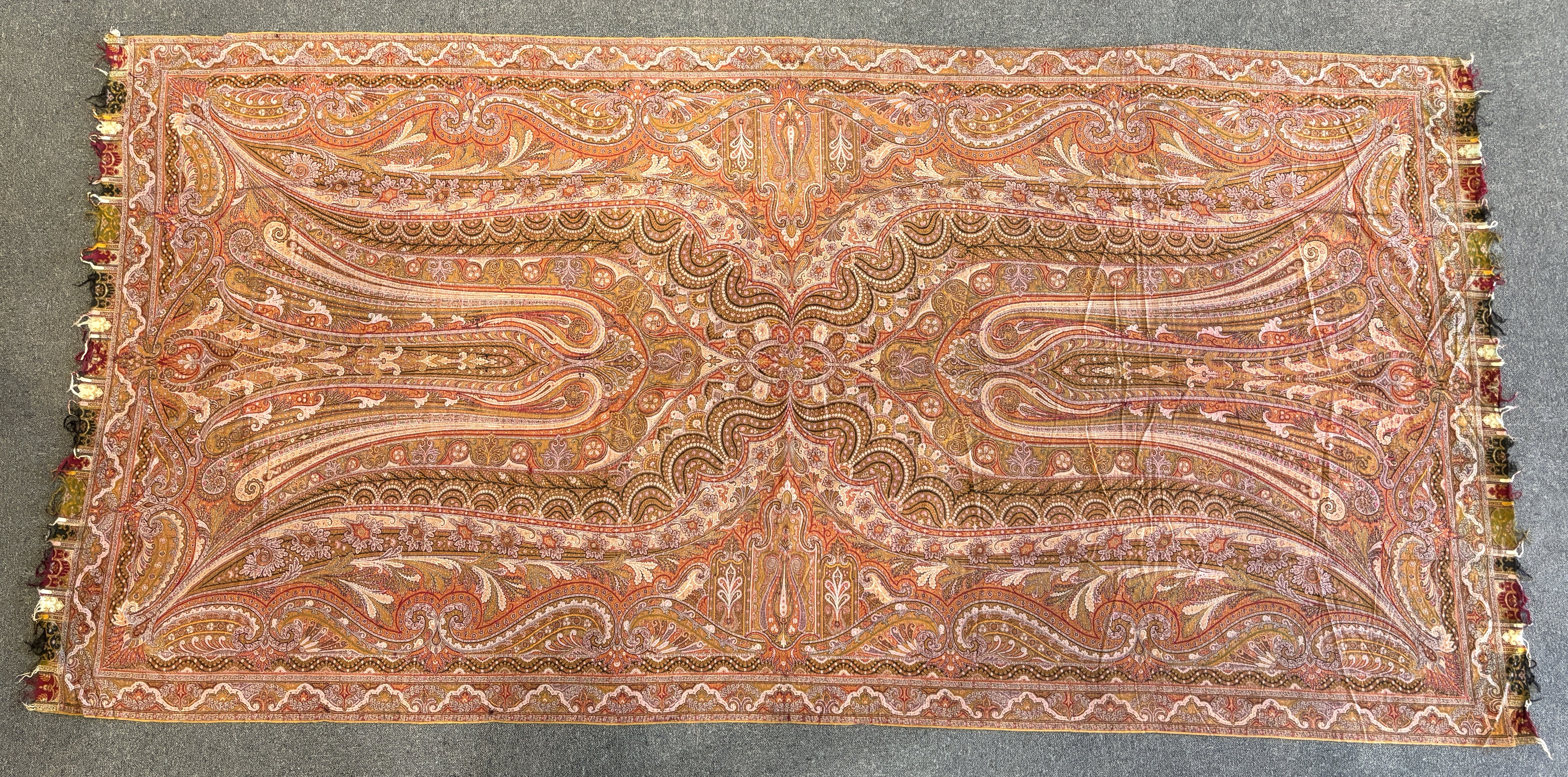 A 19th century woven Scottish Paisley wool shawl, bordered on four sides and fringed on two, woven with two ornate teardrop designs and a central cartouche, 334cm long x 160cm wide